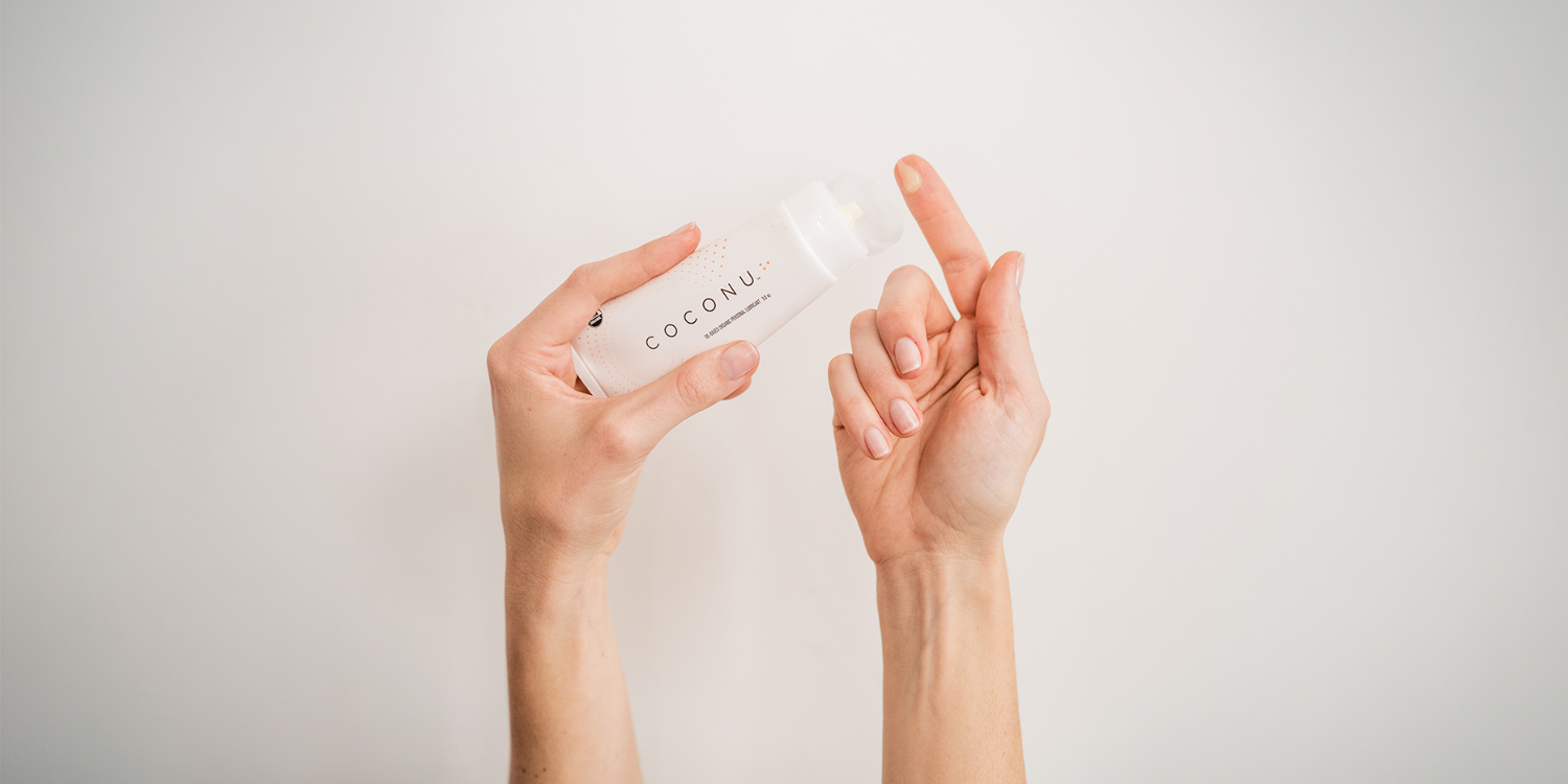 Coconu oil-based lubricant beside natural ingredients on a clean surface, representing the sea buckthorn oil and organic botanicals in the formula