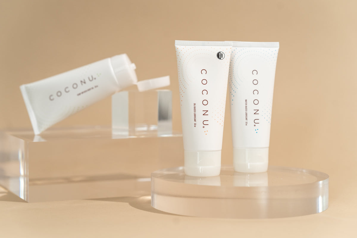 Coconu oil-based and water-based lubricant tubes on a clean surface, representing toy-safe lubricant options