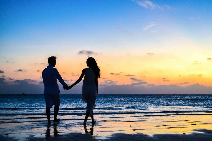 A couple holding hands and walking on the beach