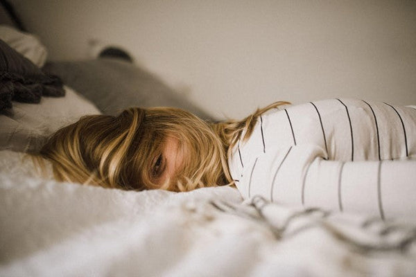 Woman lying on her stomach in bed smiling