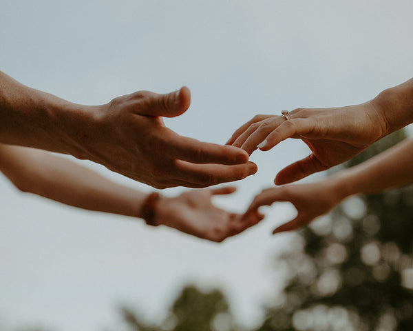man and woman reaching out for each other’s hands outside
