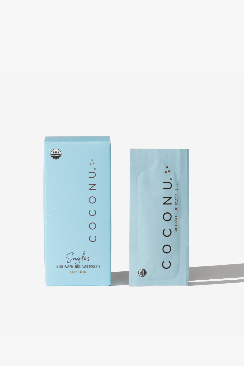 Coconu oil-based singles carton with a single-use sachet standing alongside