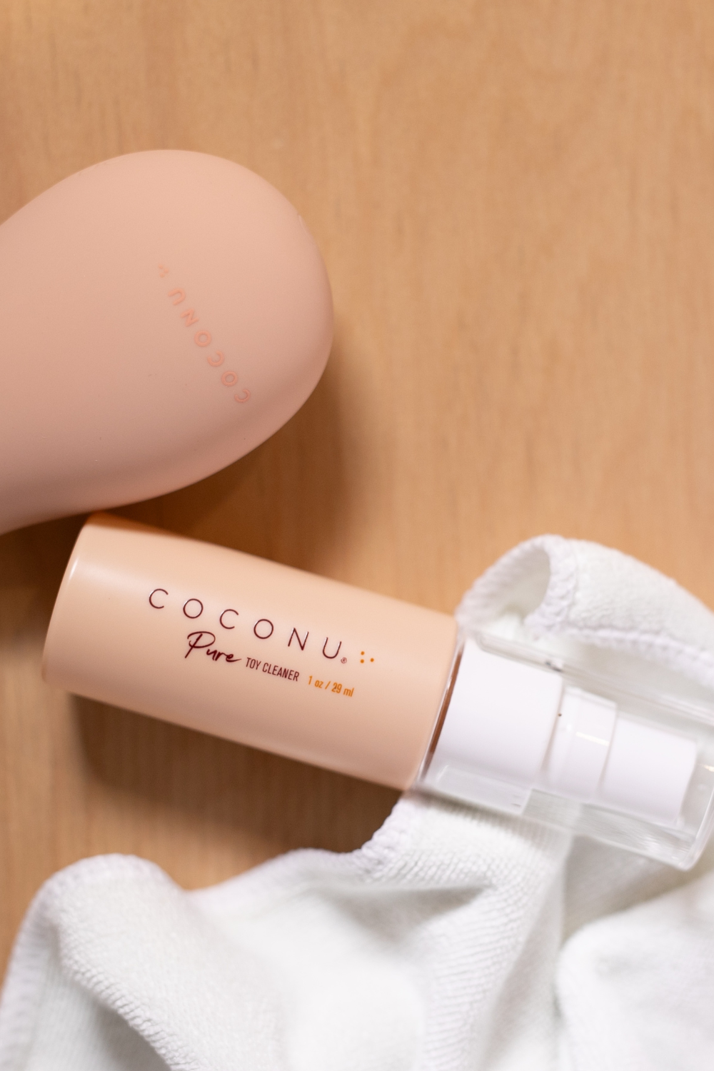Coconu Pure toy cleaner and the peach Wave massager on a white towel