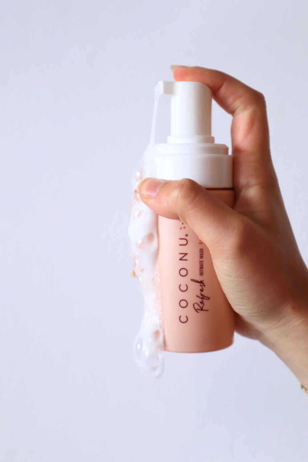 Hand pressing the Coconu Refresh pump, foam gathering at the nozzle