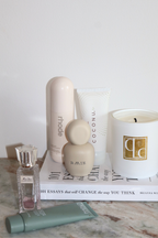 Coconu body oil tube on a shelf with a candle, diffuser and skincare bottles
