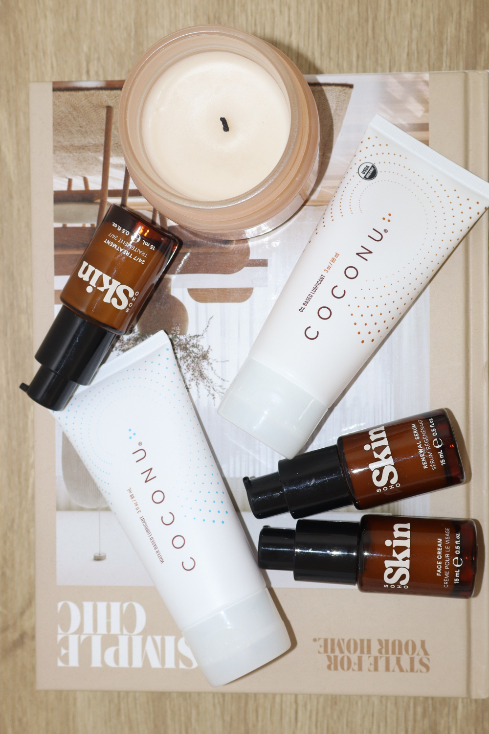 Coconu oil-based and water-based tubes in a flat lay with skincare bottles and a candle