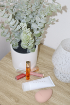 Coconu Wave massager and tube on a table with lip products and a potted plant