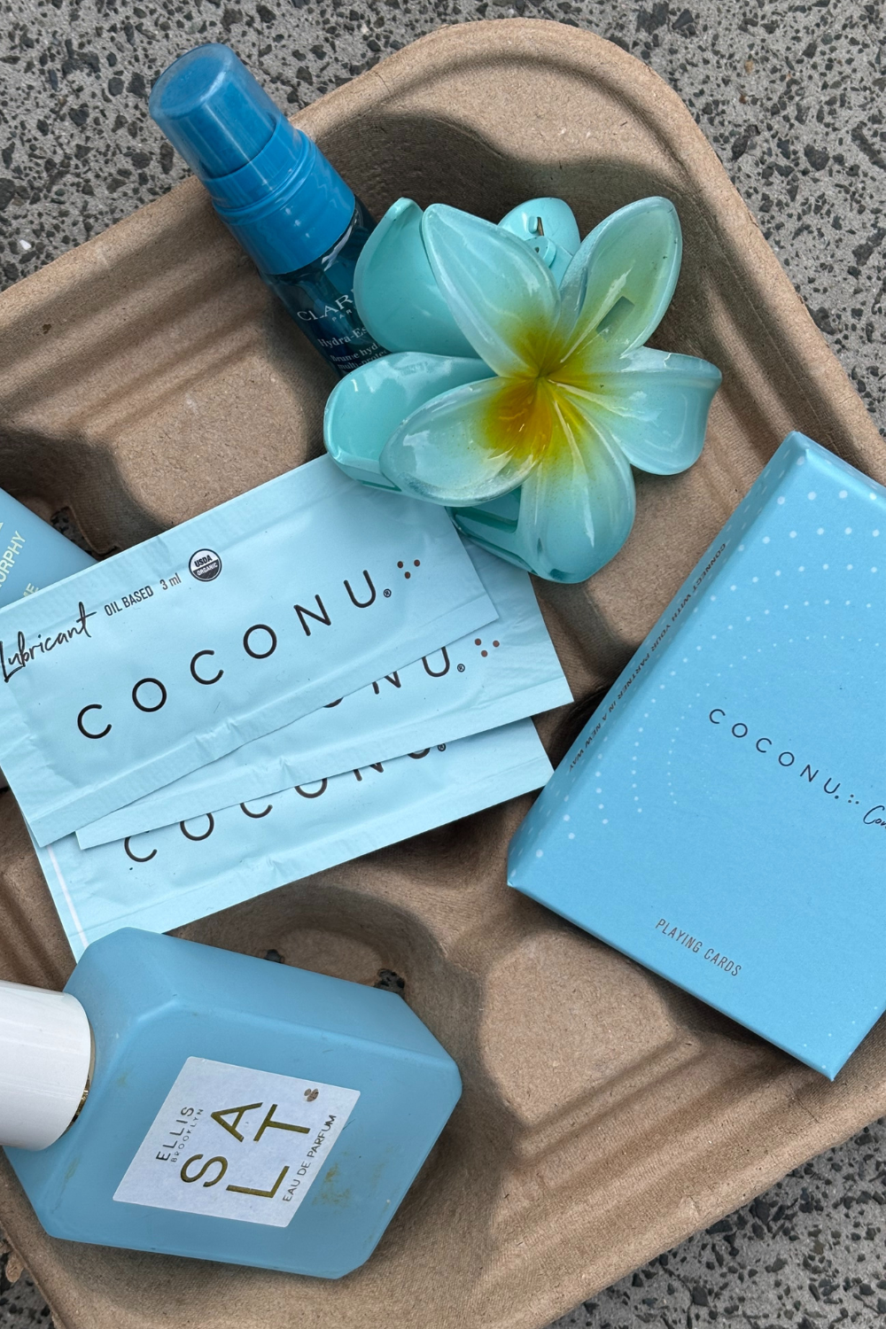 Coconu Connect cards and single-use lubricant sachets on a tray with a frangipani flower
