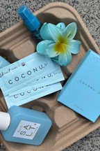 Coconu Connect cards and single-use lubricant sachets on a tray with a frangipani flower