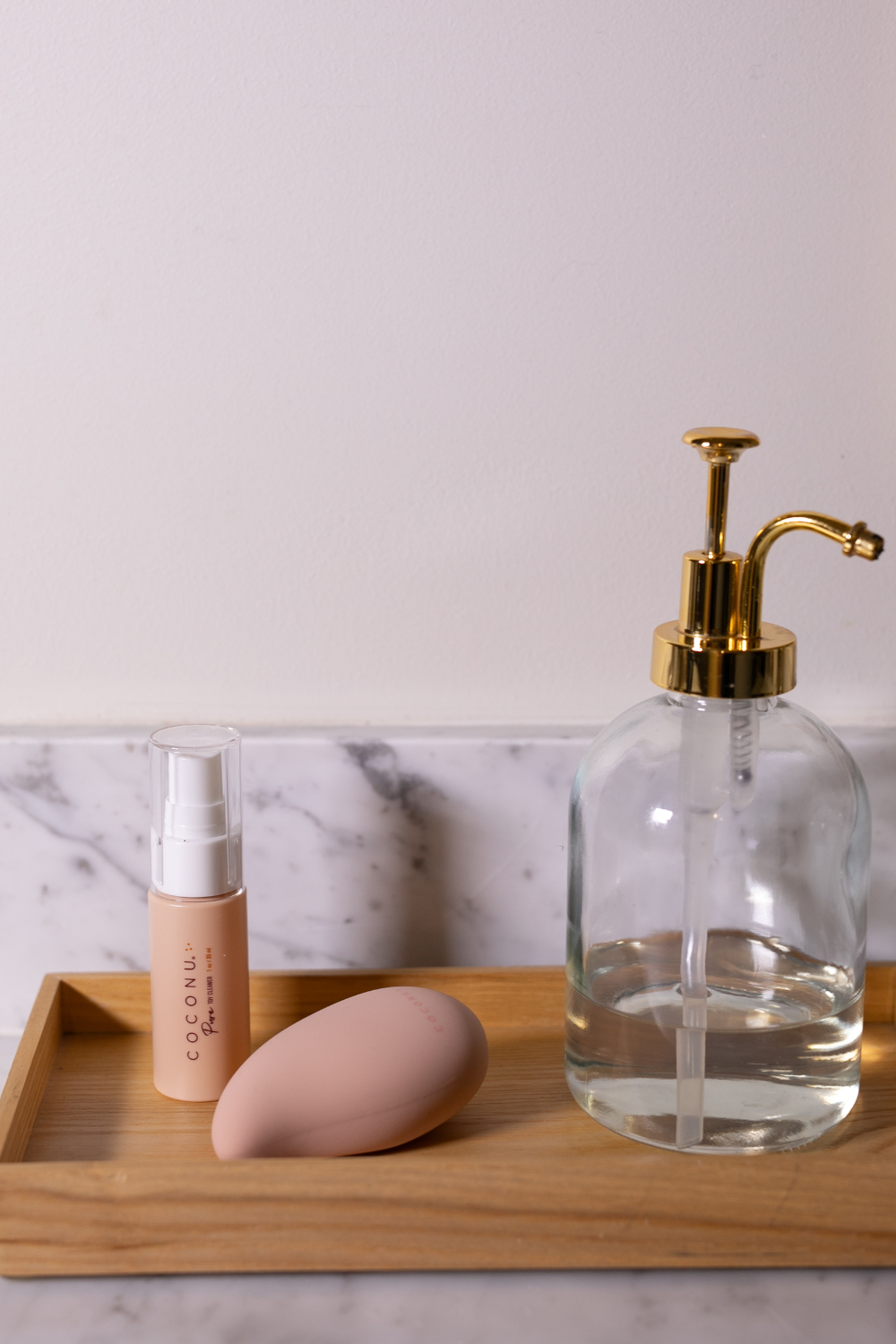 Coconu Pure toy cleaner and the Wave massager on a wooden tray with a glass soap pump