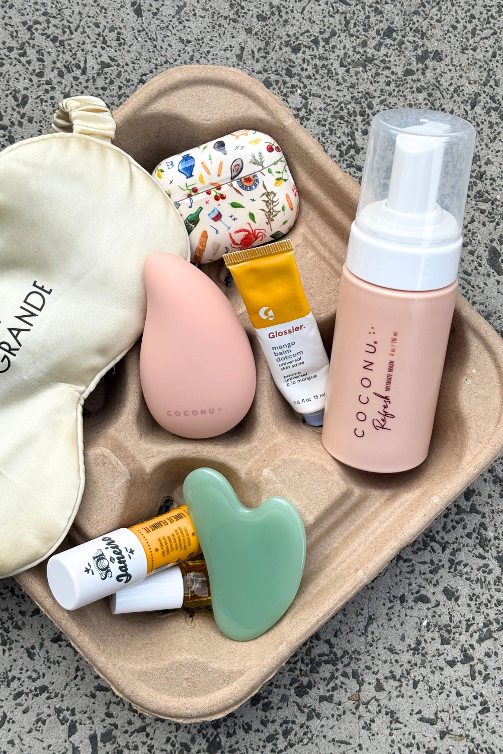 Coconu Refresh wash and the Wave massager on a tray with an eye mask and gua sha stone