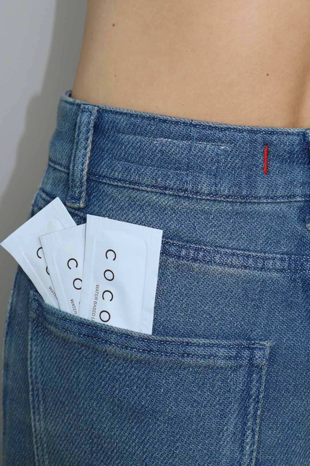 Two Coconu single-use sachets tucked into the back pocket of blue jeans