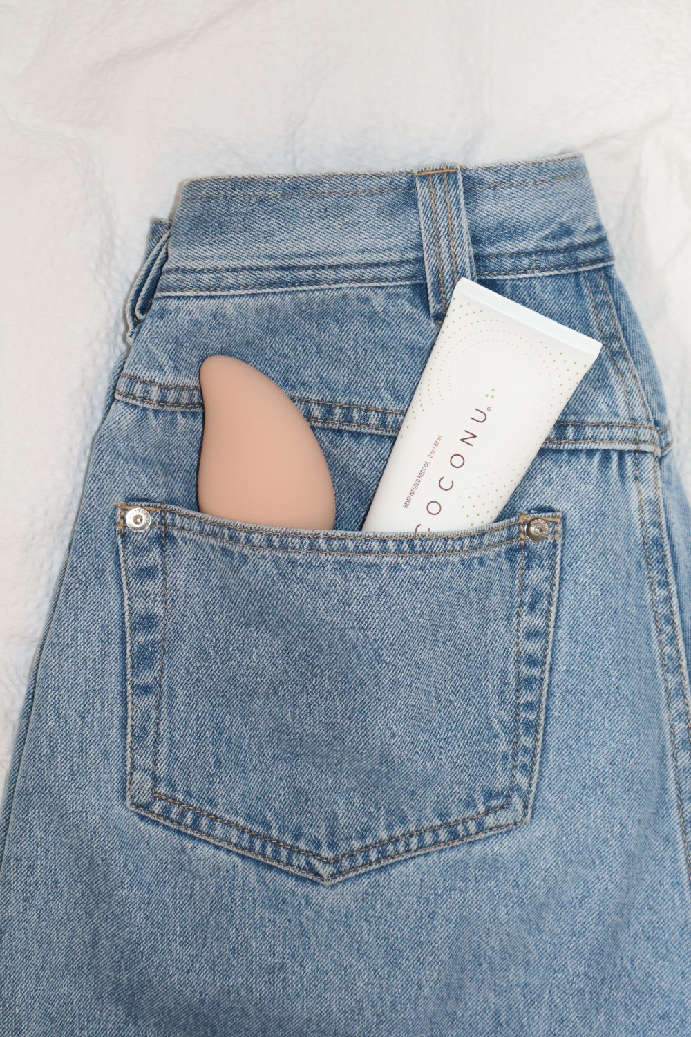 Coconu Wave massager and a Coconu tube in the back pocket of blue jeans