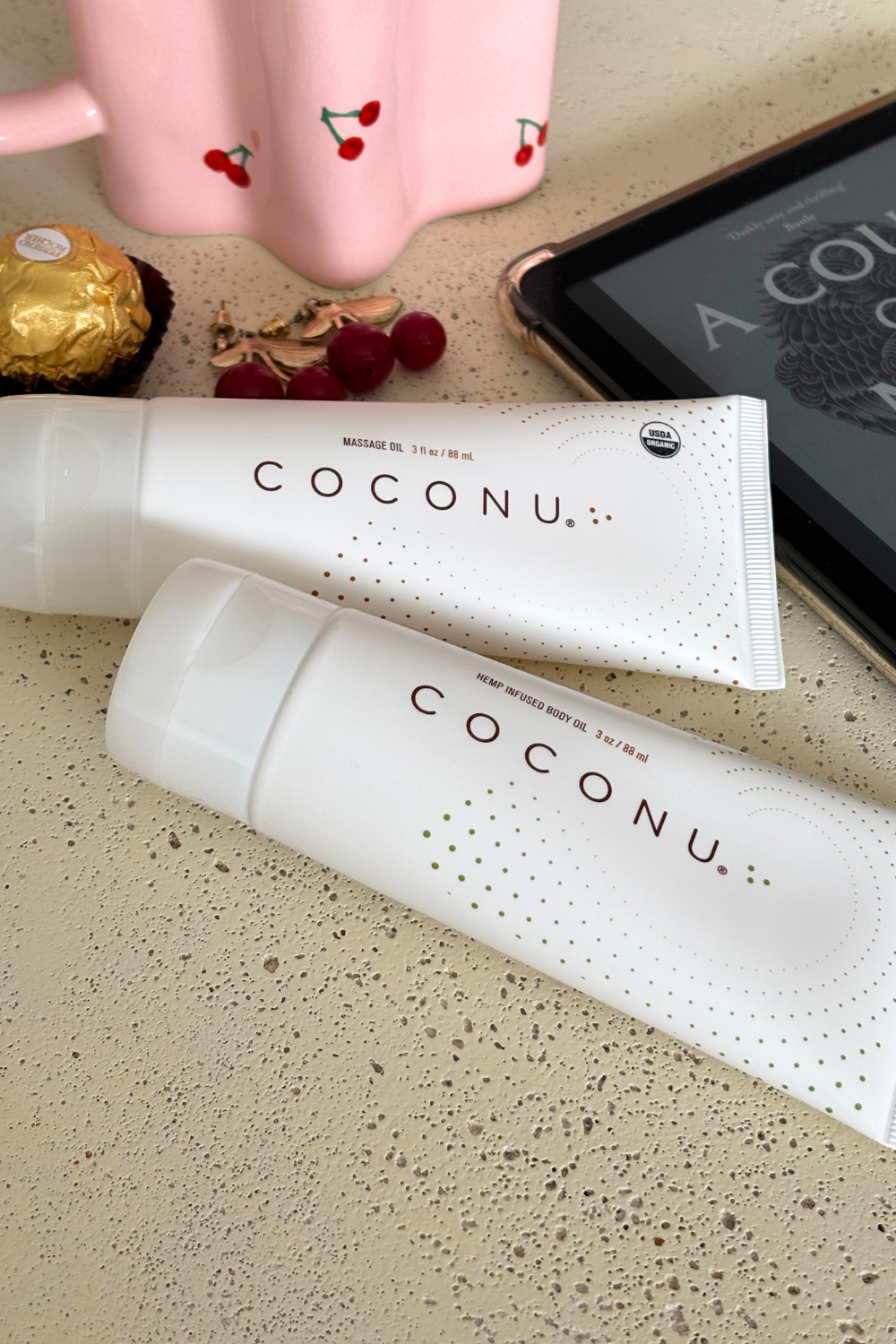 Two Coconu tubes on a sand-coloured surface with chocolates and a tablet