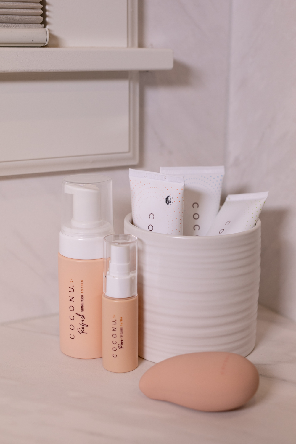 Coconu pumps and single sachets in a ribbed cup on a bathroom shelf, Wave alongside