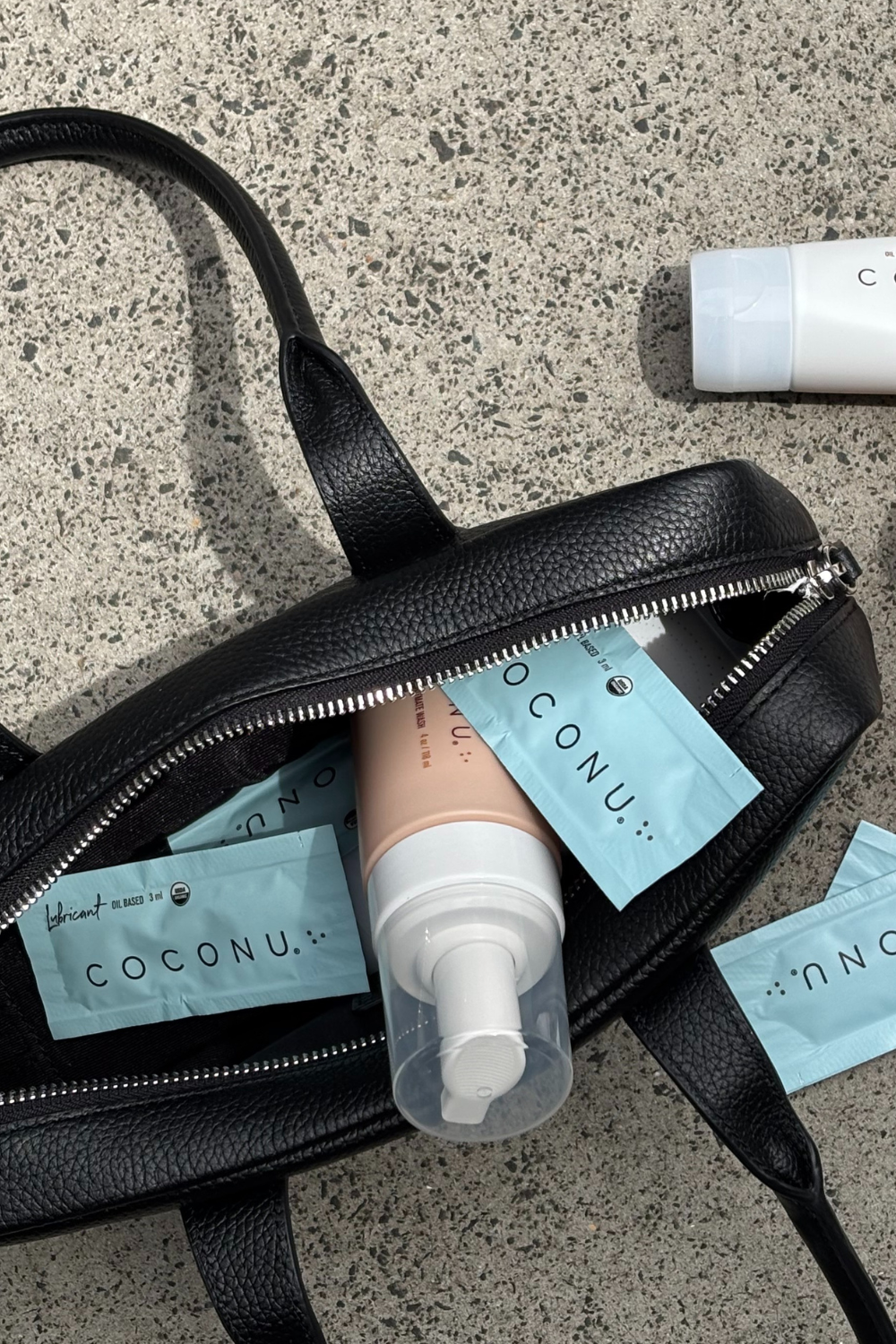 Coconu Refresh wash and single sachets spilling from a black leather tote