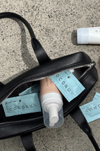 Coconu Refresh wash and single sachets spilling from a black leather tote