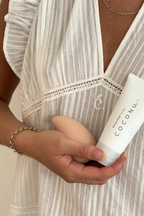 Person in a striped dress holding the Coconu Wave massager and a Coconu tube